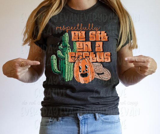 Image displays a person wearing a t-shirt and pointing to it. The shirt's design includes serif and funky block font text that read, "respecfully go sit on a cactus." A faced pumpkin, a cactus, bats, and a cowboy hat surround the design.