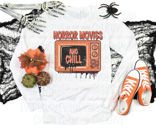 Image displays a t-shirt surrounded by Halloween-themed decorations. The shirt's design includes a vintage orange television with a dripping effect on the bottom. Halloween-themed font text above the television reads, "horror movies" and on the television, it reads, "and chill."