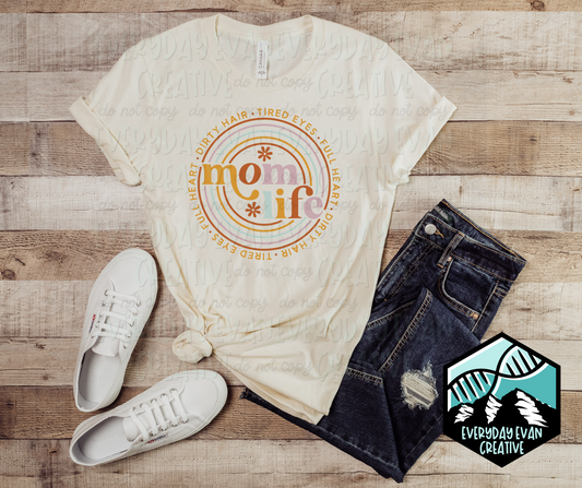 Image of a Mom Life Tee with dirty hair, tired eyes, full heart, around the design. 